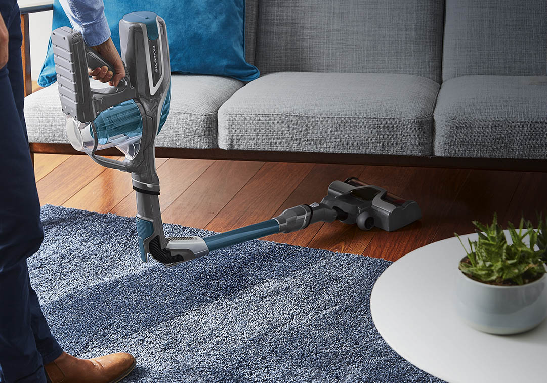 Man vacuuming under a sofa